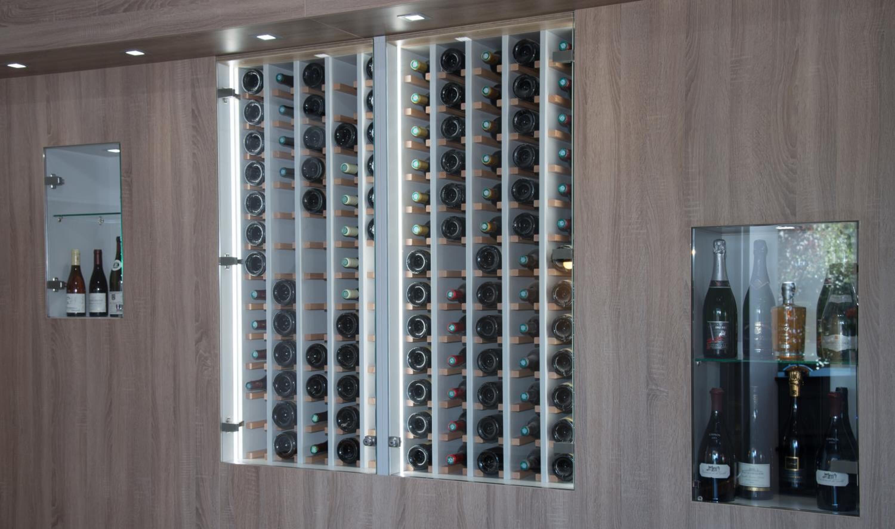 Una botellera con varias botellas, un espejo y un cuadro en la pared.