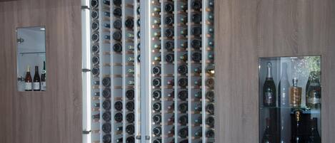 Una botellera con varias botellas, un espejo y un cuadro en la pared.