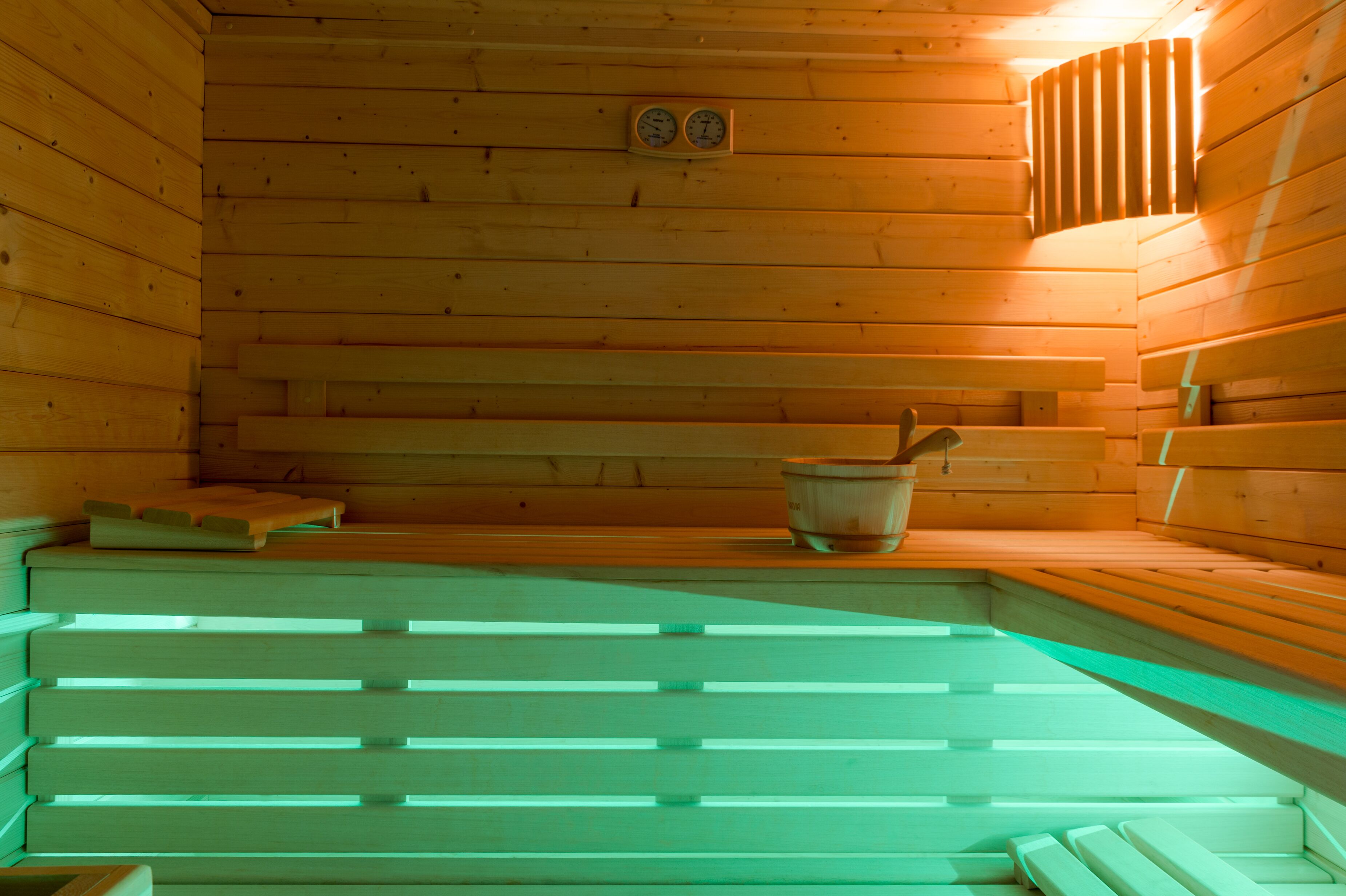 Un sauna avec des bancs en bois et un bassin en pierre.
