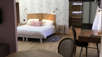 A bedroom with a wooden bed, a bedside table, a chair, and a small table with a lamp.