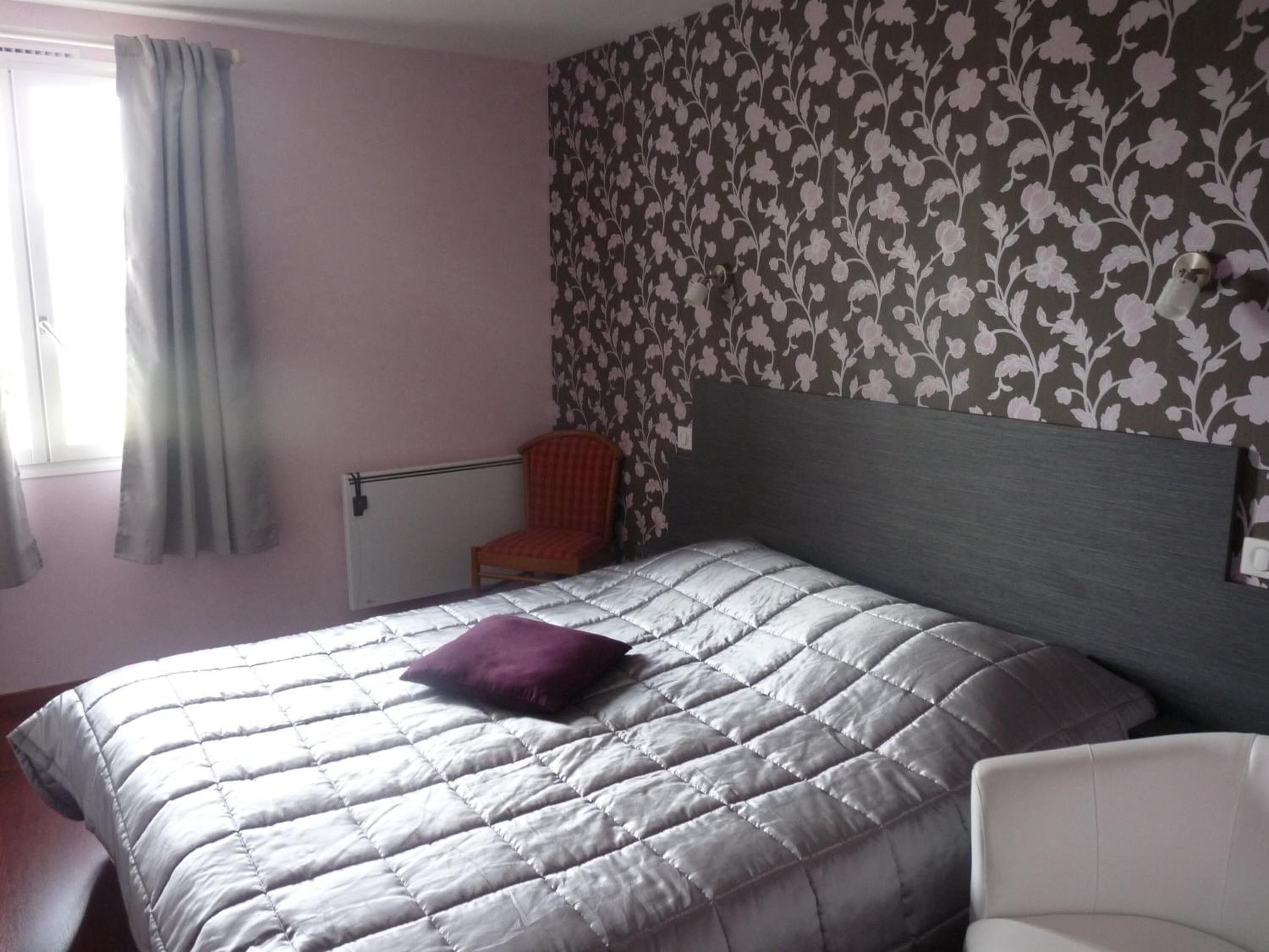 A bedroom with a bed, a chair, and a radiator.