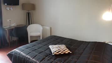 Una habitación con una cama, un escritorio, una silla y un televisor en la pared.