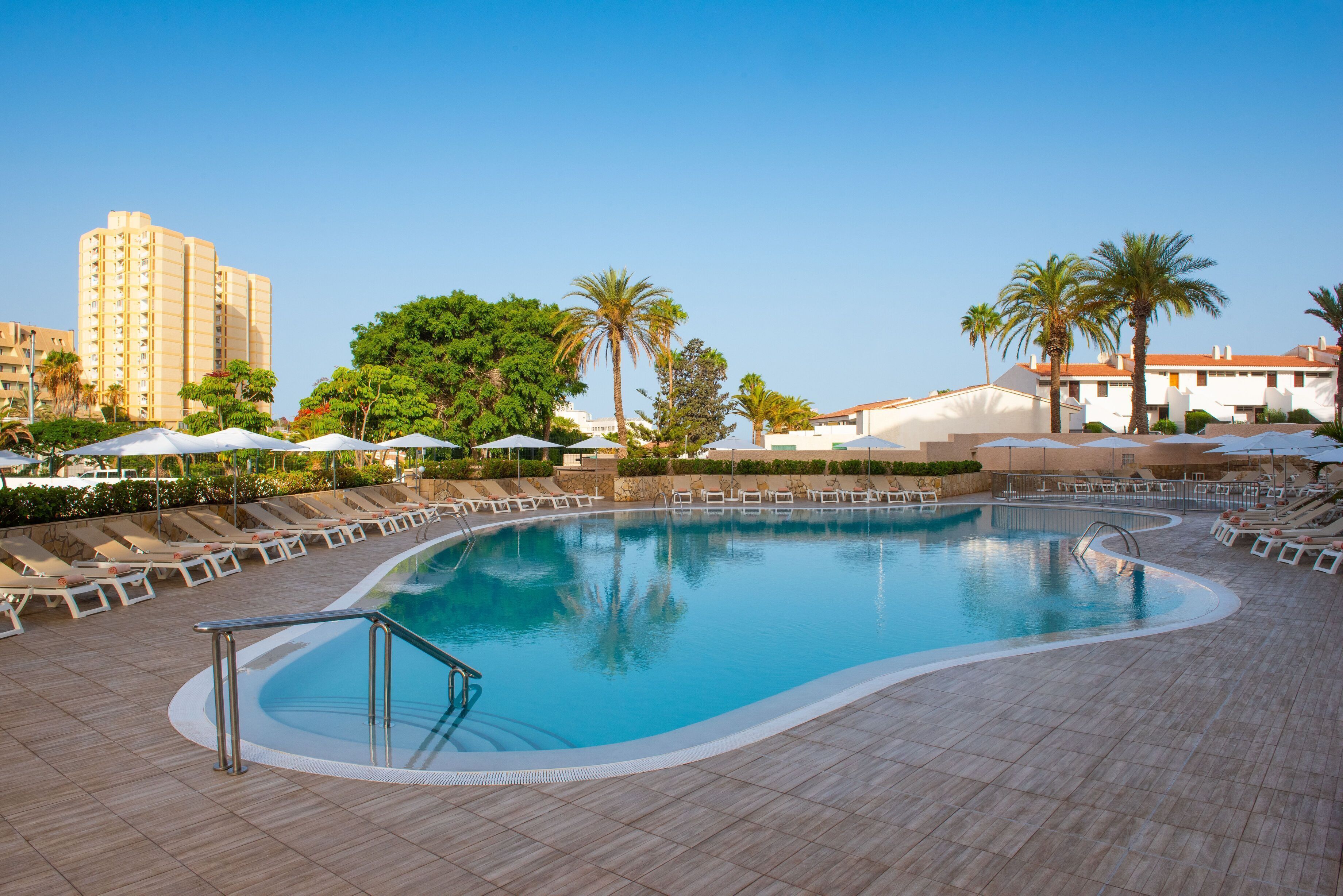 Een buitenzwembad, parasols voor strand/zwembad