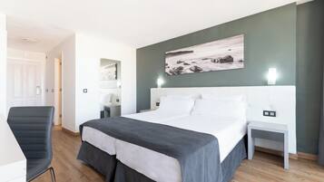 Un dormitorio moderno con una cama grande, una silla, una mesita de noche y una obra de arte colgada en la pared.