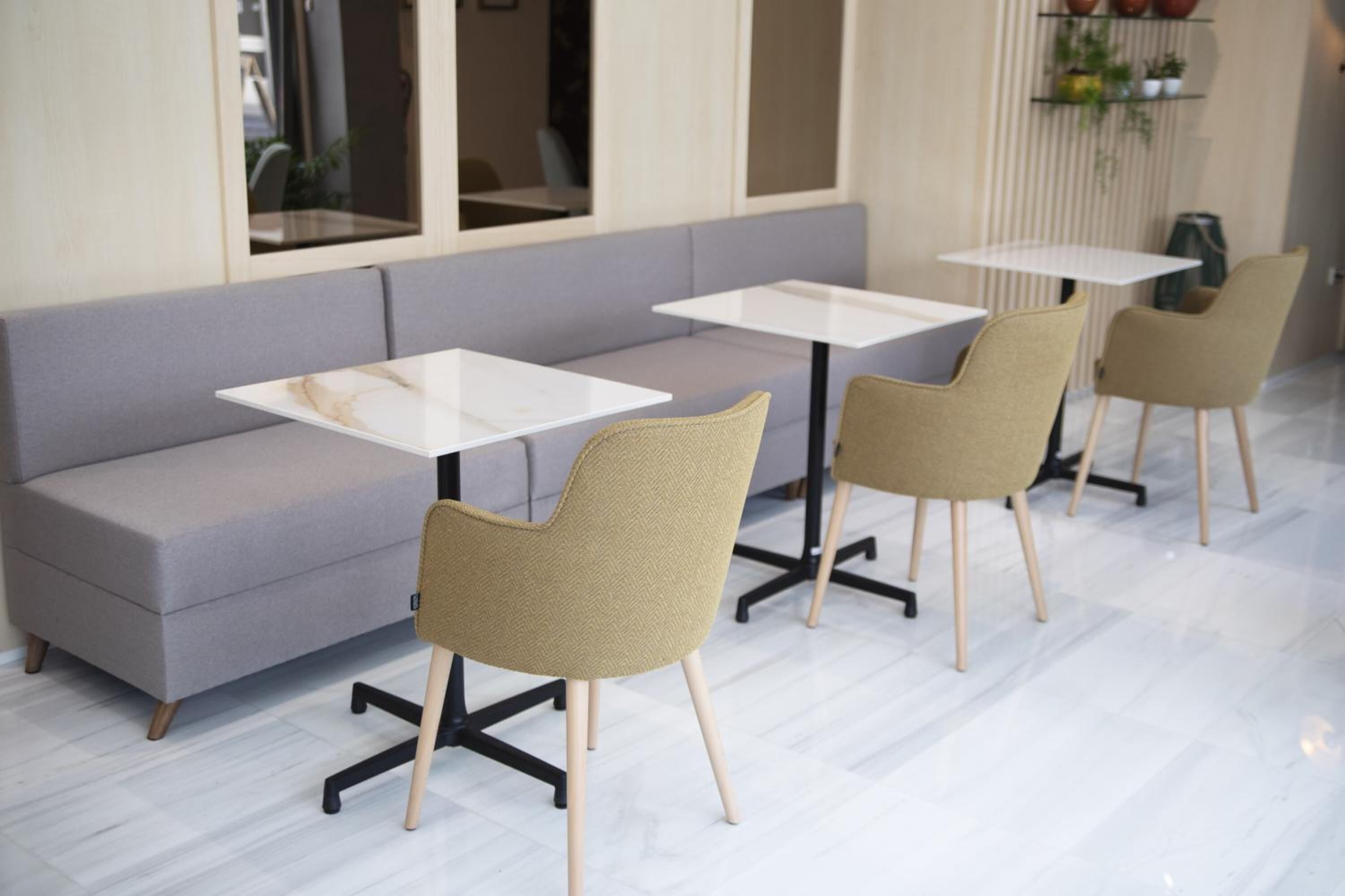 A modern interior with a grey sofa, two white tables, and two chairs.
