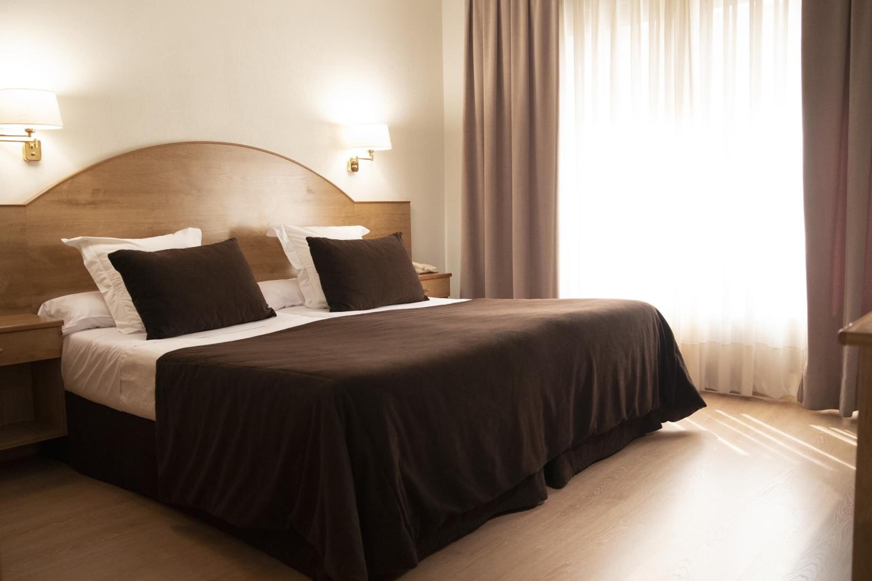 Une chambre d’hôtel avec un grand lit, deux tables de chevet et une tête de lit.