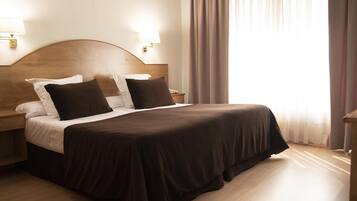 Une chambre d’hôtel avec un grand lit, deux tables de chevet et une tête de lit.