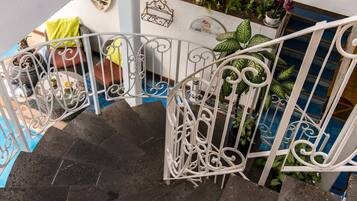 A spiral staircase with white metal railings, surrounded by potted plants and a blue mat.