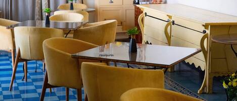 Un comedor con sillas amarillas y una mesa, una zona de cocina con armarios y electrodomésticos, y un ventilador de techo.