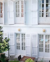 Un edificio de dos pisos con contraventanas y balcones blancos.
