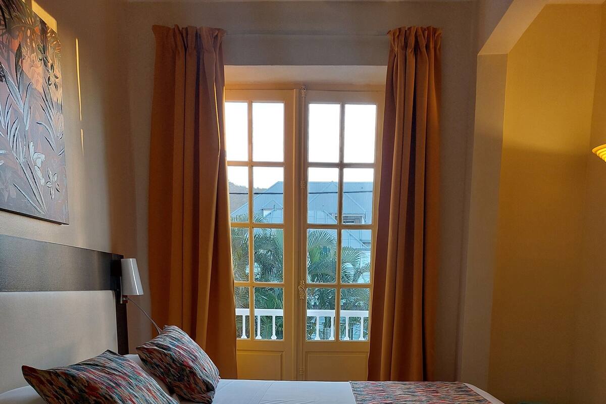 Une chambre d’hôtel avec un lit, un tableau au mur et une vue par la fenêtre.
