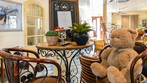 A cozy interior with wicker chairs, a table with a menu, and a teddy bear. - Hotel le Juliette Dodu (Saint-Denis)