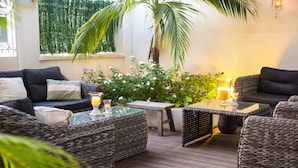 A cozy outdoor seating area with wicker furniture, a small table, and a potted plant. - Hotel le Juliette Dodu (Saint-Denis)