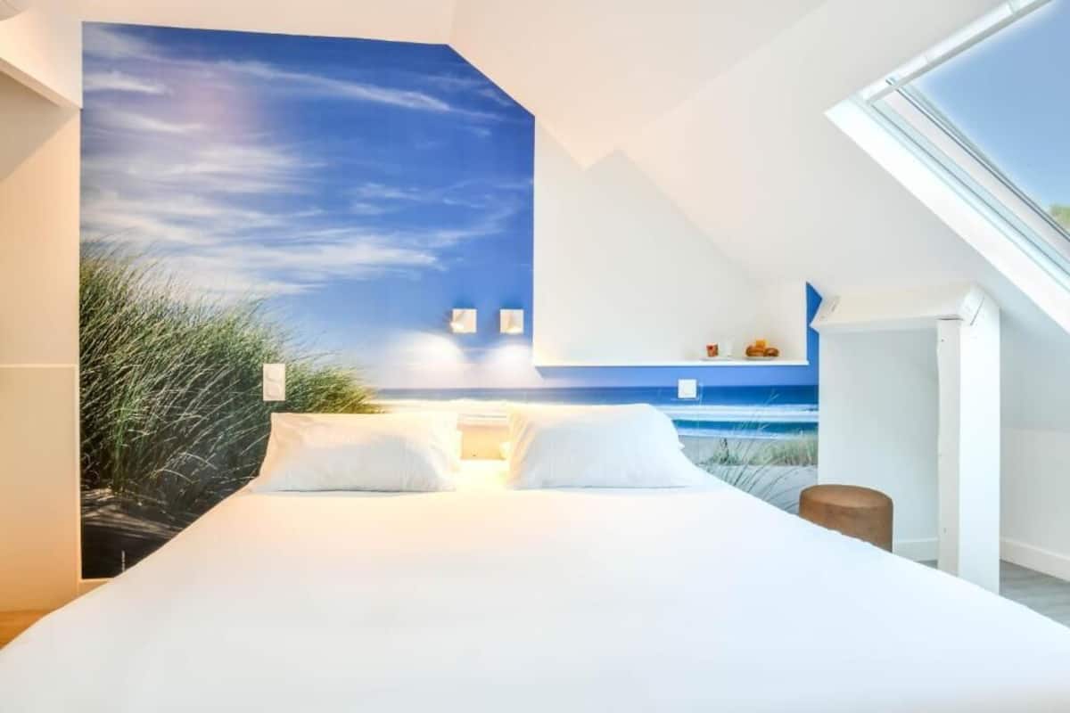 A bedroom with a large bed, a skylight, and a view of the beach through a mural.