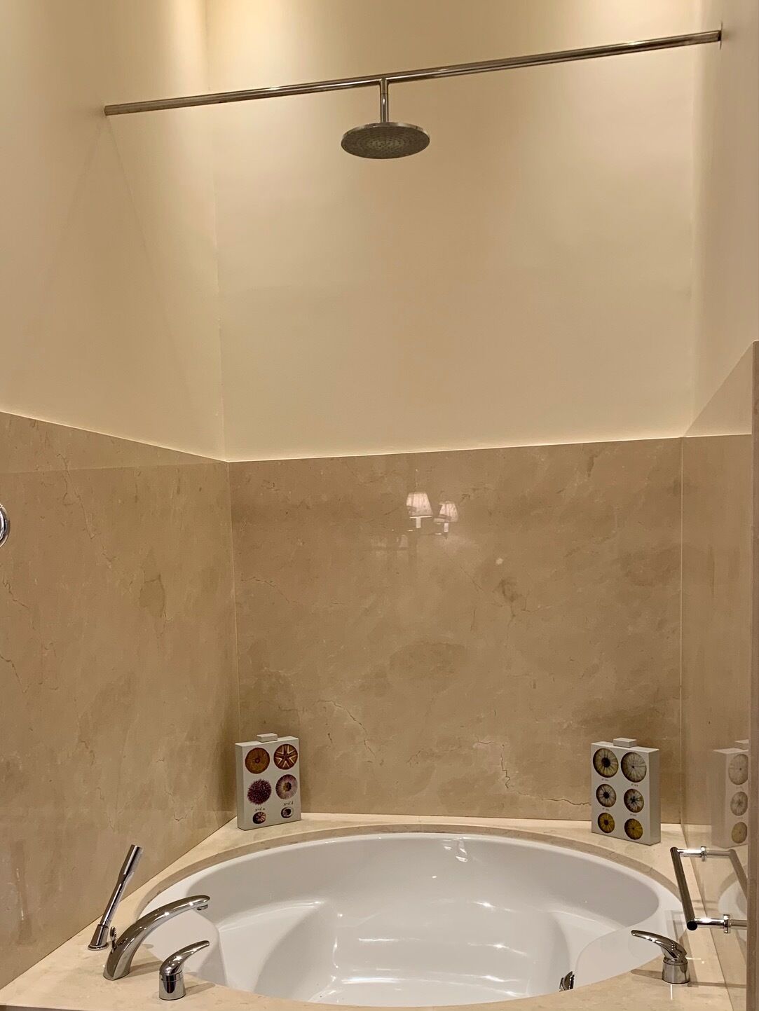 A modern bathroom with a freestanding bathtub, a handheld showerhead, and a set of speakers on the wall.