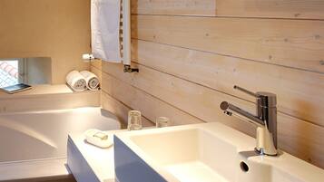 Un baño moderno con pared de madera, una bañera, un lavabo y dos toallas enrolladas.