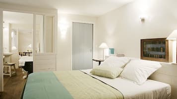 A bedroom with a bed, bedside lamps, a mirror, a dresser, and a window with a view.