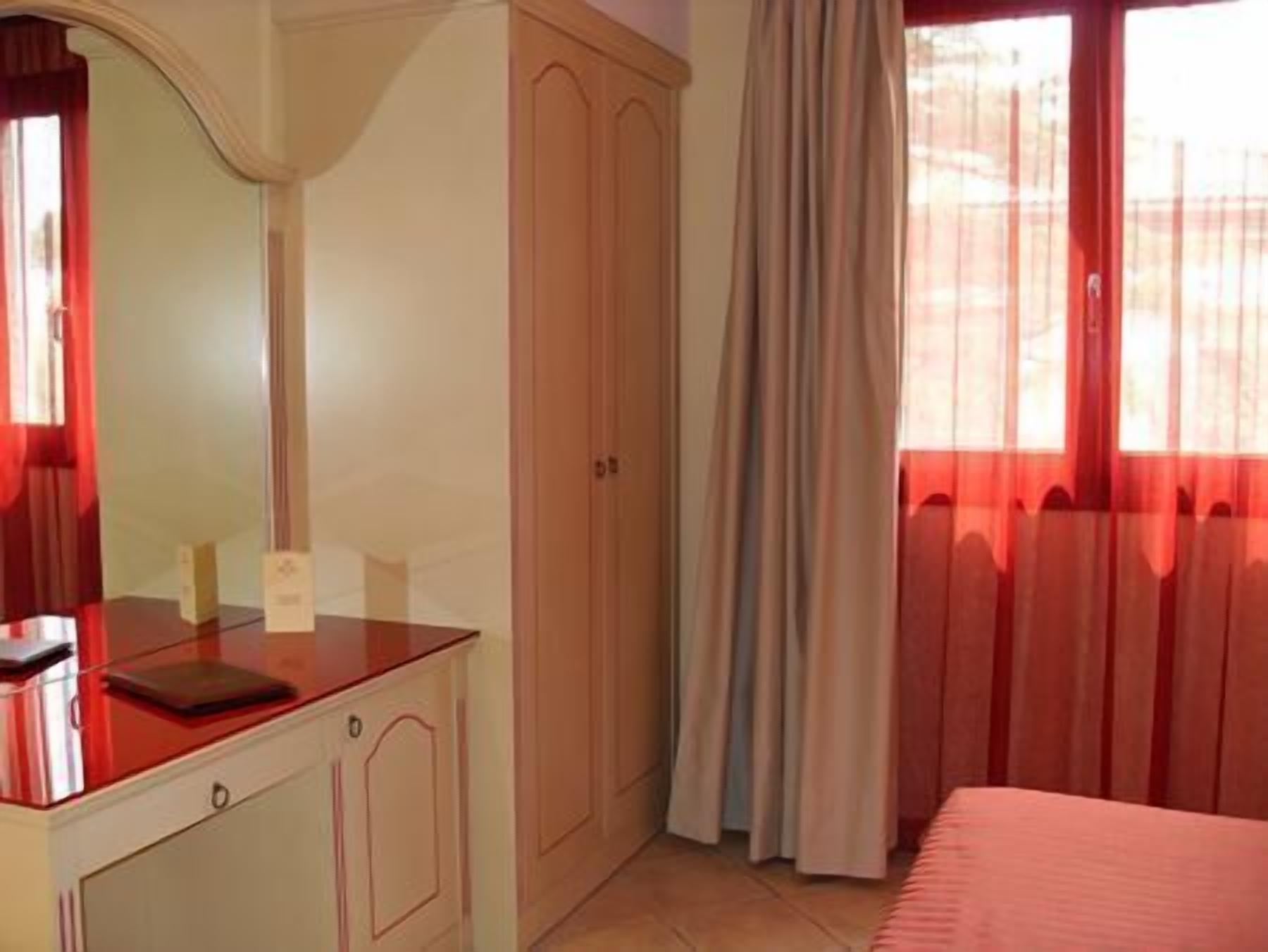 A bedroom with a bed, a dresser, a mirror, and a window with curtains.
