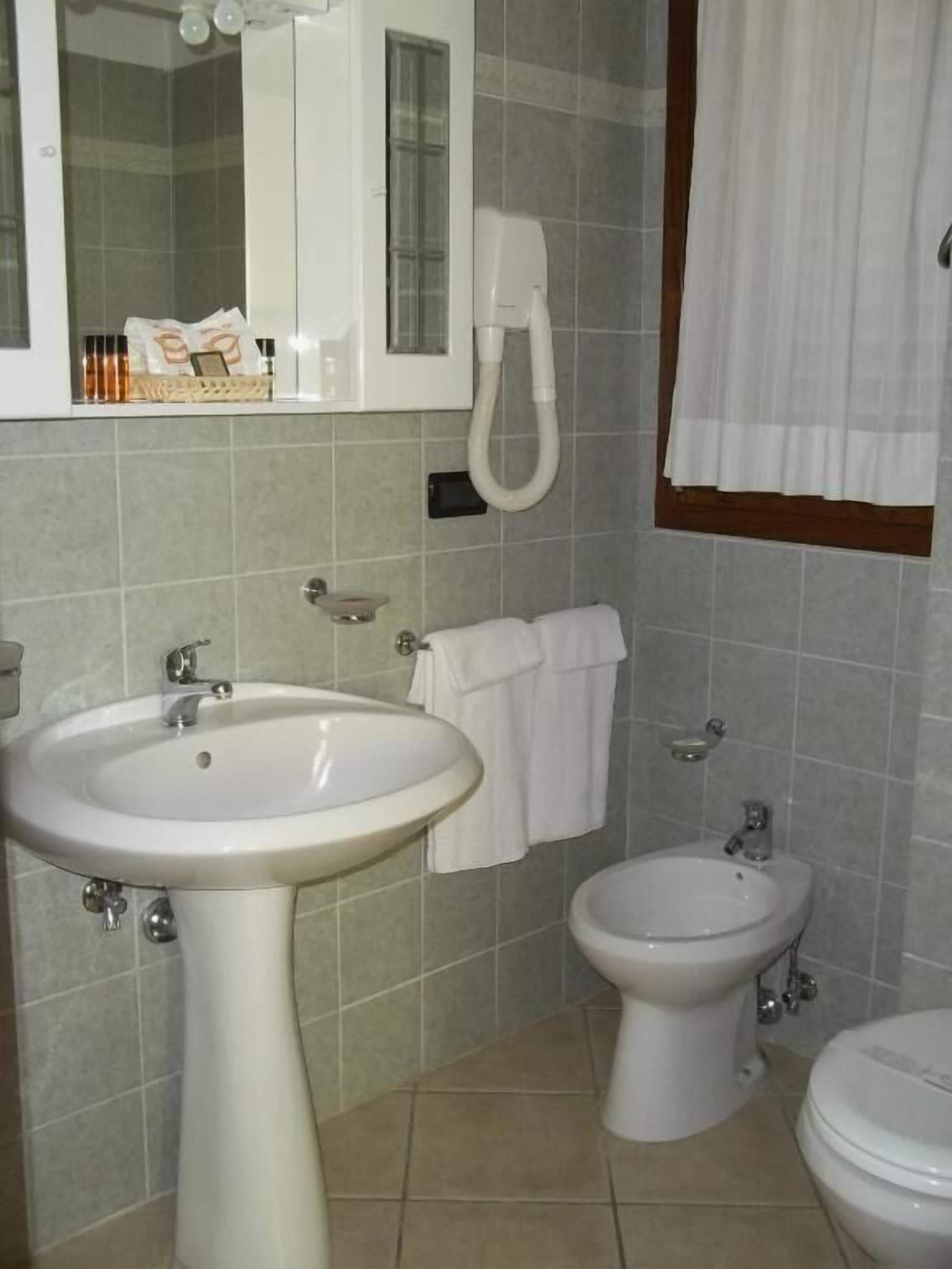 Ein Badezimmer mit einem Standwaschbecken, einer Toilette und einem Bidet.