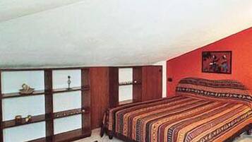 A bedroom with a bed, a window with blinds, a rug, and a painting on the wall.