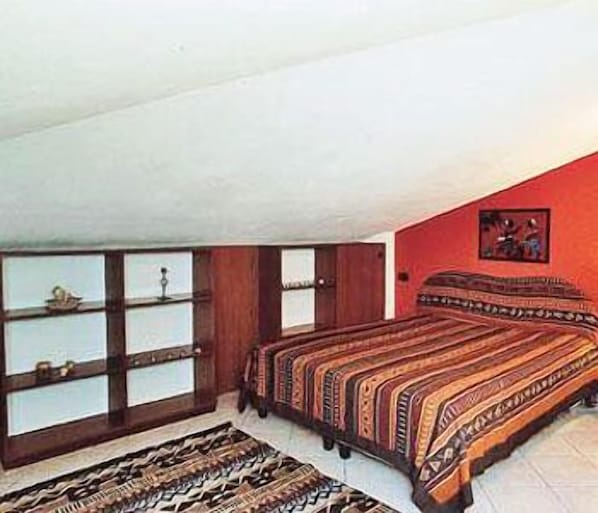 Une chambre à coucher avec un lit, une fenêtre avec des stores, un tapis et un tableau accroché au mur.
