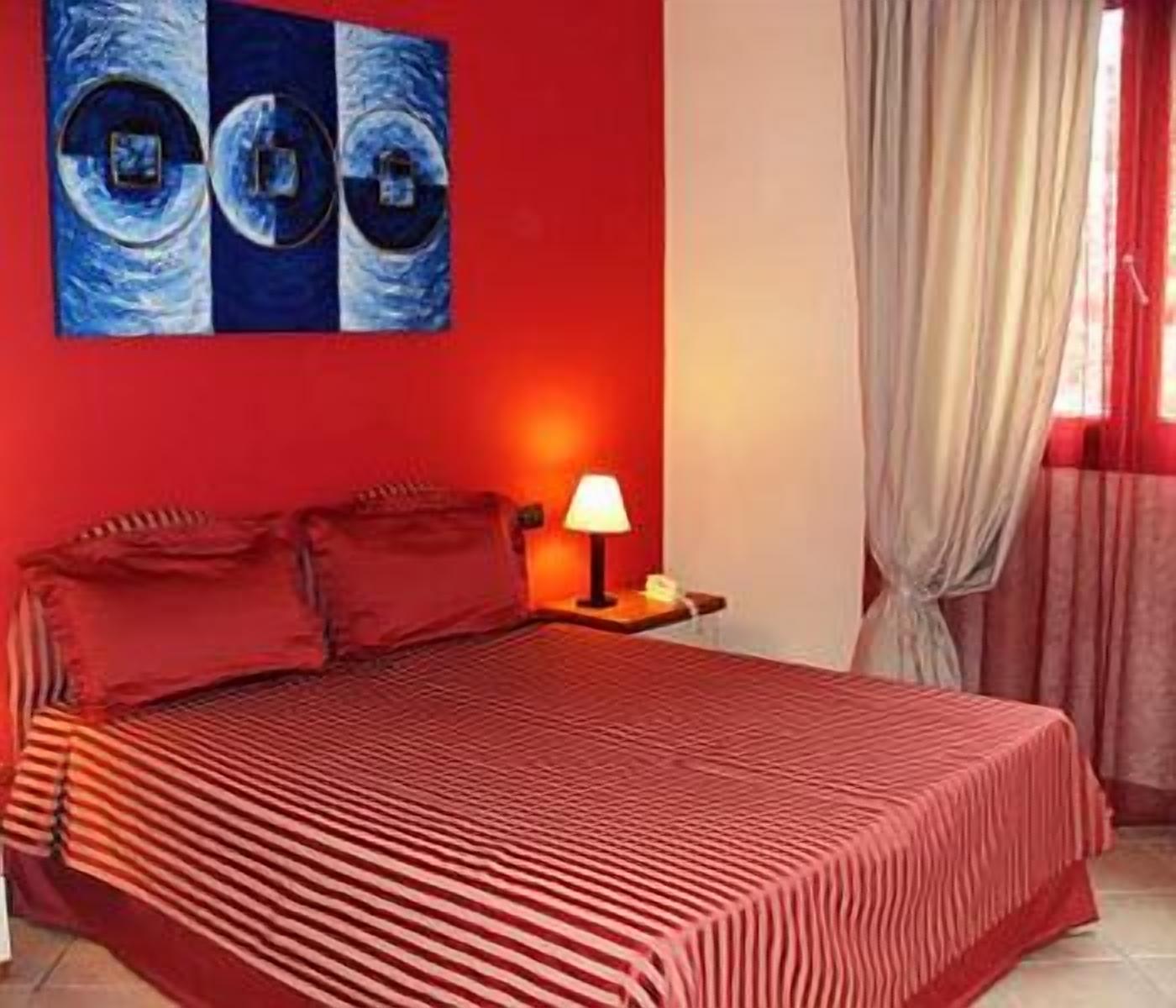 Una habitación con una cama, una mesita de noche, una lámpara y un cuadro en la pared.