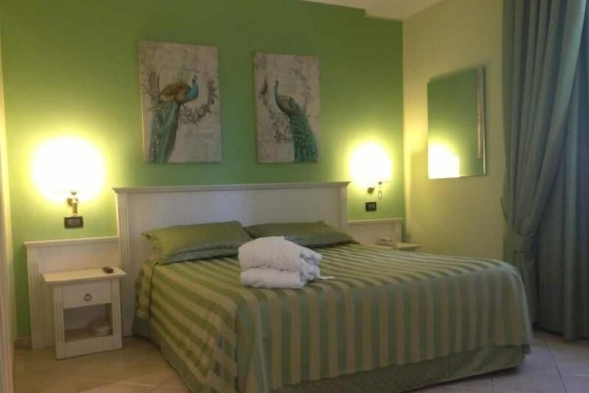Un dormitorio con una cama, dos lámparas de pared, una mesita de noche y un espejo.