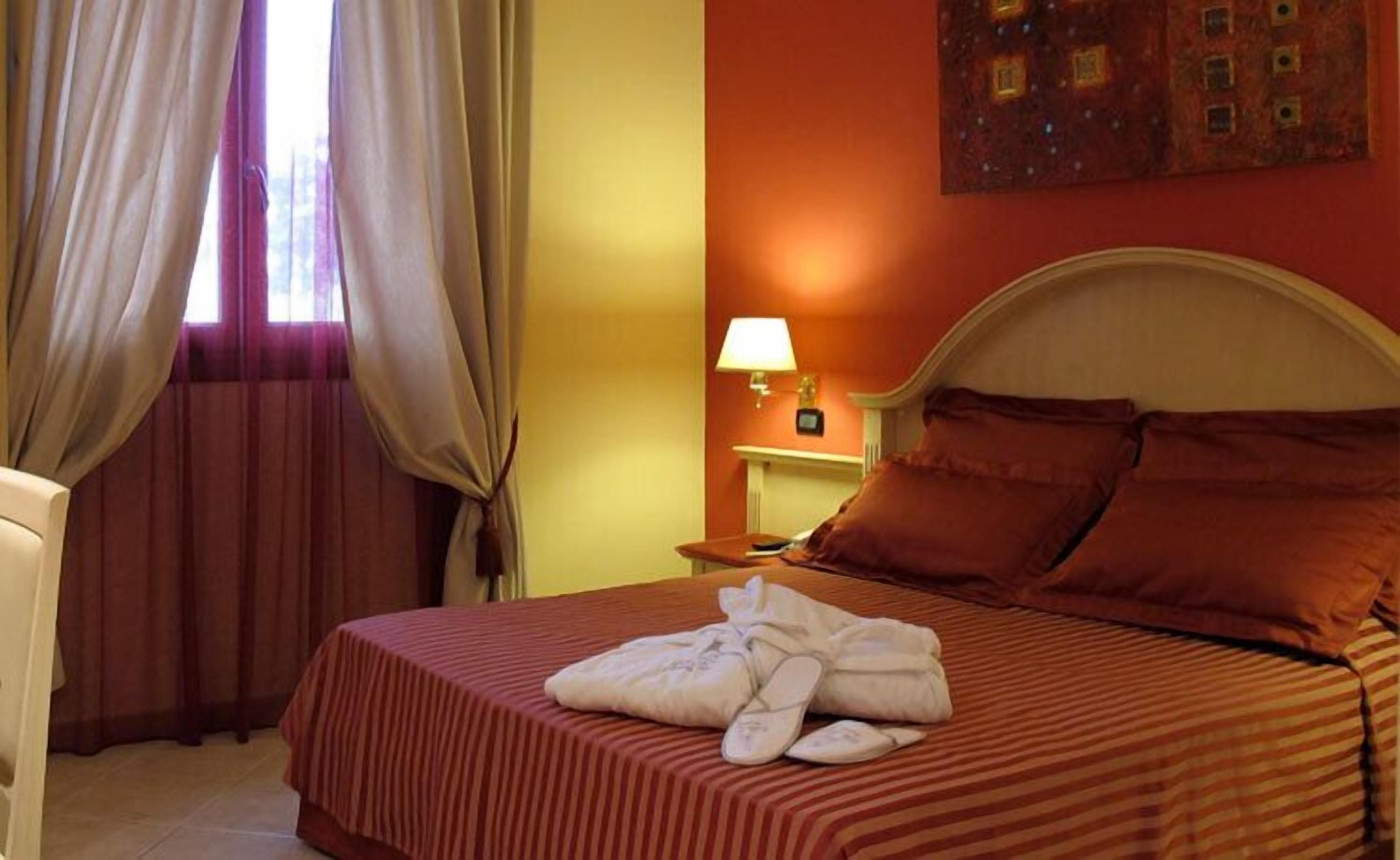 Una habitación de hotel con una cama, una mesita de noche, una lámpara y un cuadro en la pared.