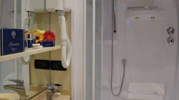 A bathroom with a shower, a sink, and a shelf with toiletries.