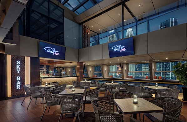 A restaurant with high ceilings, large windows, and city views.