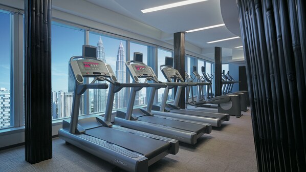 Un gimnasio moderno con cintas de correr, bicicletas estáticas y un amplio ventanal con vistas a la ciudad.
