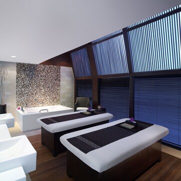 A modern spa room with two large tubs, a reception desk, and a wall with a textured mosaic pattern.
