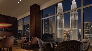 A modern dining area with large windows overlooking the Petronas Towers at night. - Traders Hotel Kuala Lumpur (Kuala Lumpur)
