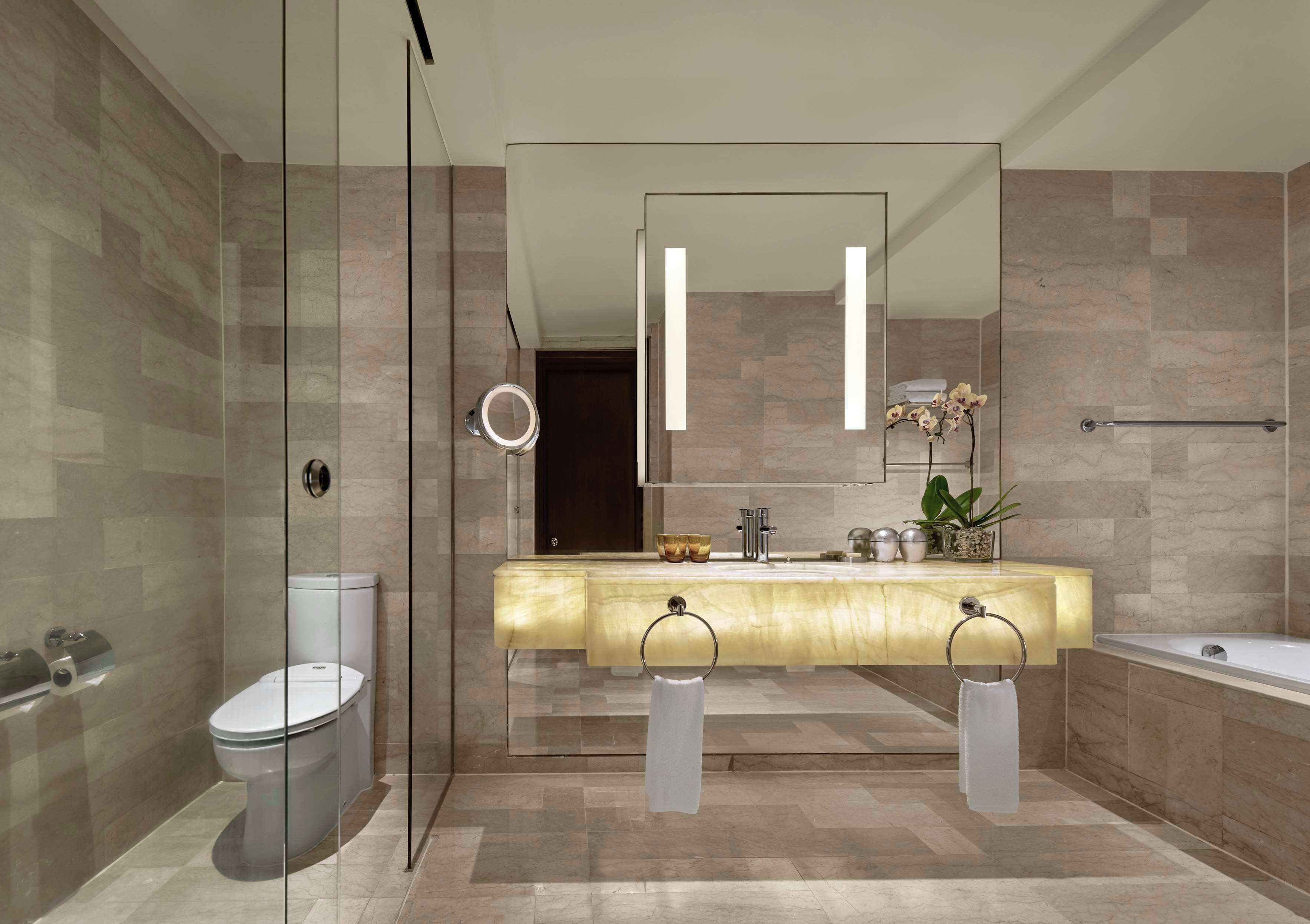 A modern bathroom with a glass-enclosed shower, a toilet, a vanity with a mirror, and a bathtub.