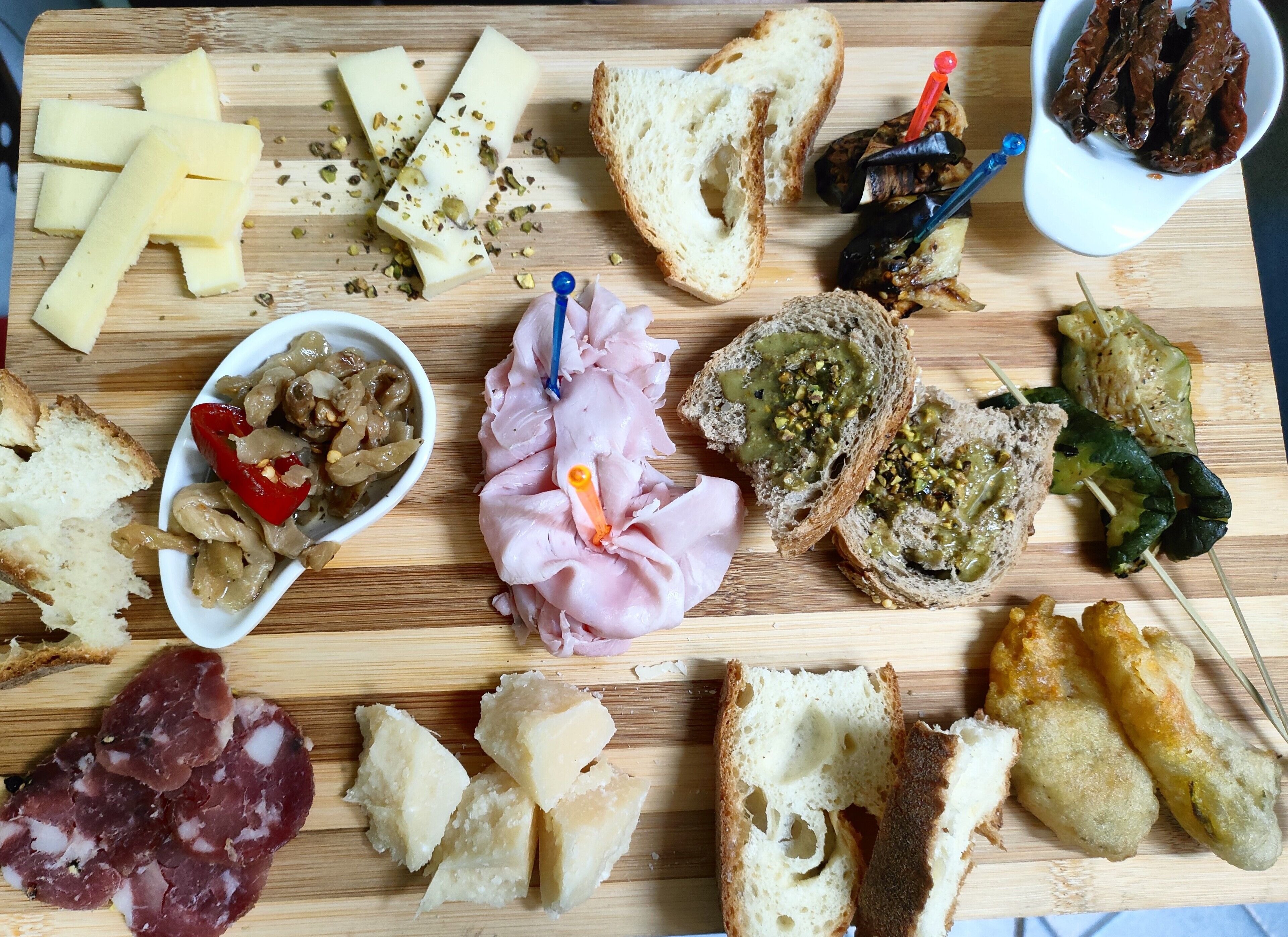 Una variedad de alimentos como queso, pan y embutidos dispuestos sobre una tabla de madera.