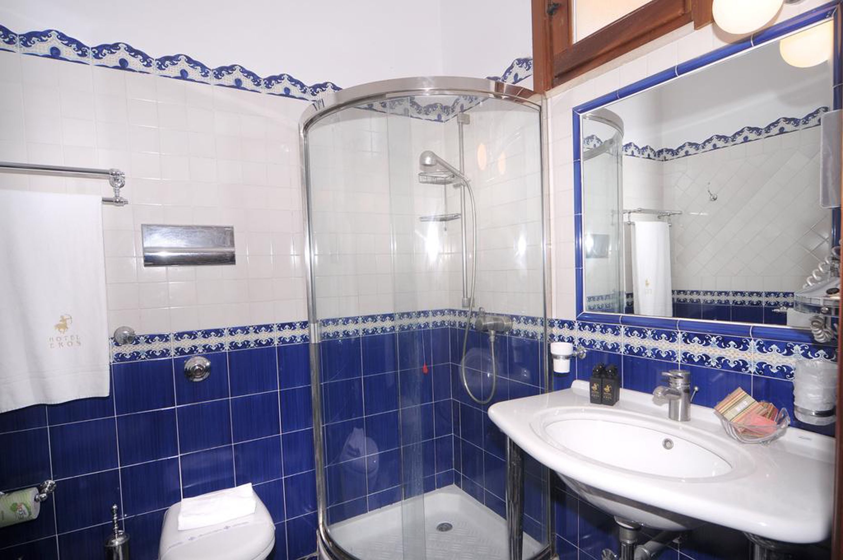 A bathroom with a glass-enclosed shower, a white sink, and a mirror.