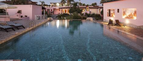 A swimming pool with lounge chairs and a stone deck.
