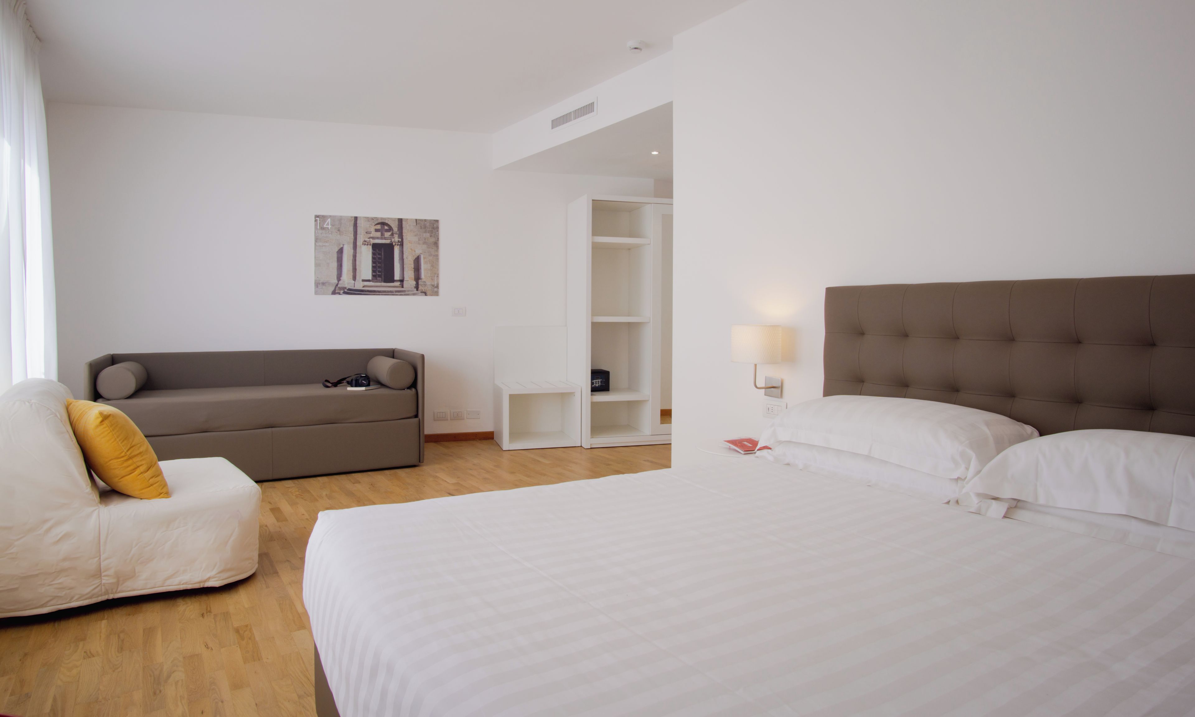 Ein Hotelzimmer mit einem Bett, einer Couch, einem kleinen Tisch und einem an der Wand befestigten Regal.