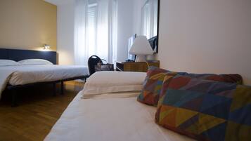 Une chambre d’hôtel avec deux lits, un canapé, un bureau avec une lampe et une fenêtre avec des rideaux.