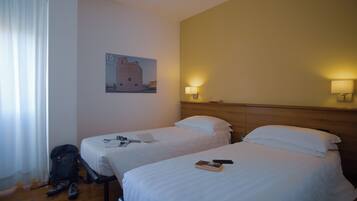 Een hotelkamer met twee bedden, een houten hoofdbord, een wandlamp en een lijst met een afbeelding.