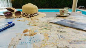 A map of Golfo di Oristano on a table with a straw hat, sunglasses, and a pen. - Hotel Mistral 2 (Oristano)