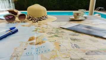 Un mapa del Golfo di Oristano sobre una mesa, junto a un sombrero de paja, gafas de sol y un bolígrafo.