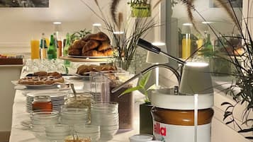 Una mesa de buffet con diversos alimentos, entre ellos frutas, pasteles y salsas.