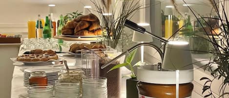 A buffet table with various food items, including fruits, pastries, and condiments.