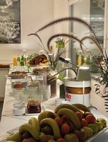 Una mesa de buffet con diversos alimentos, entre ellos frutas, pasteles y salsas.