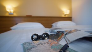 A bed with a map, a pen, and a pair of glasses on it. - Hotel Mistral 2 (Oristano)