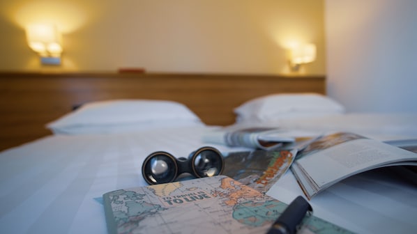 Una cama con un mapa, un bolígrafo y un par de gafas.
