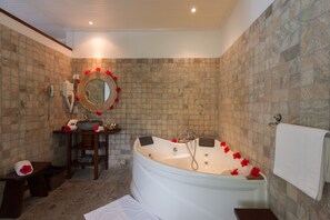 A bathroom with a freestanding bathtub, a wooden vanity, a mirror, and a towel rack. - Le Relax Beach Resort - Praslin (Praslin Island)