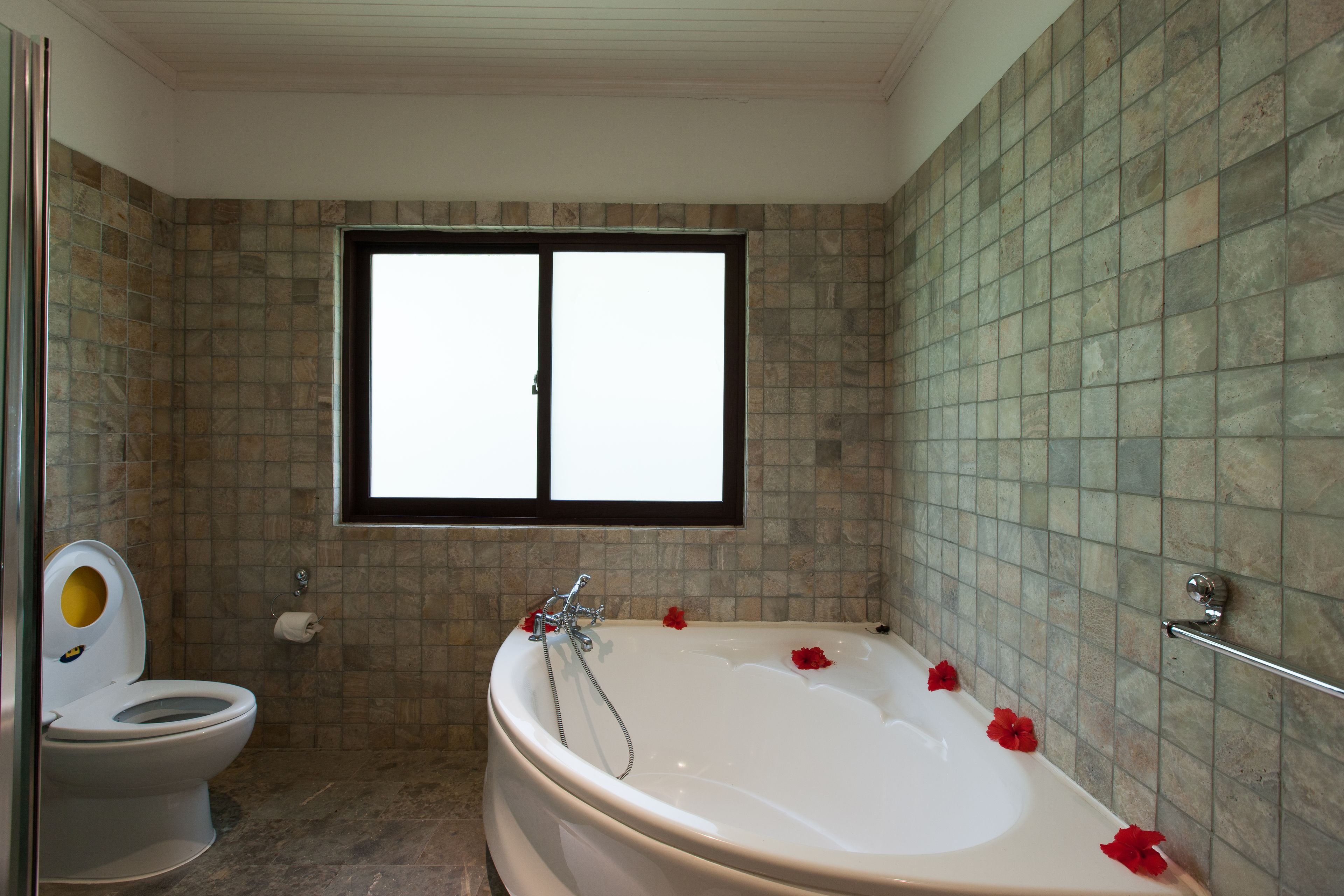A bathroom with a bathtub, toilet, and a window.