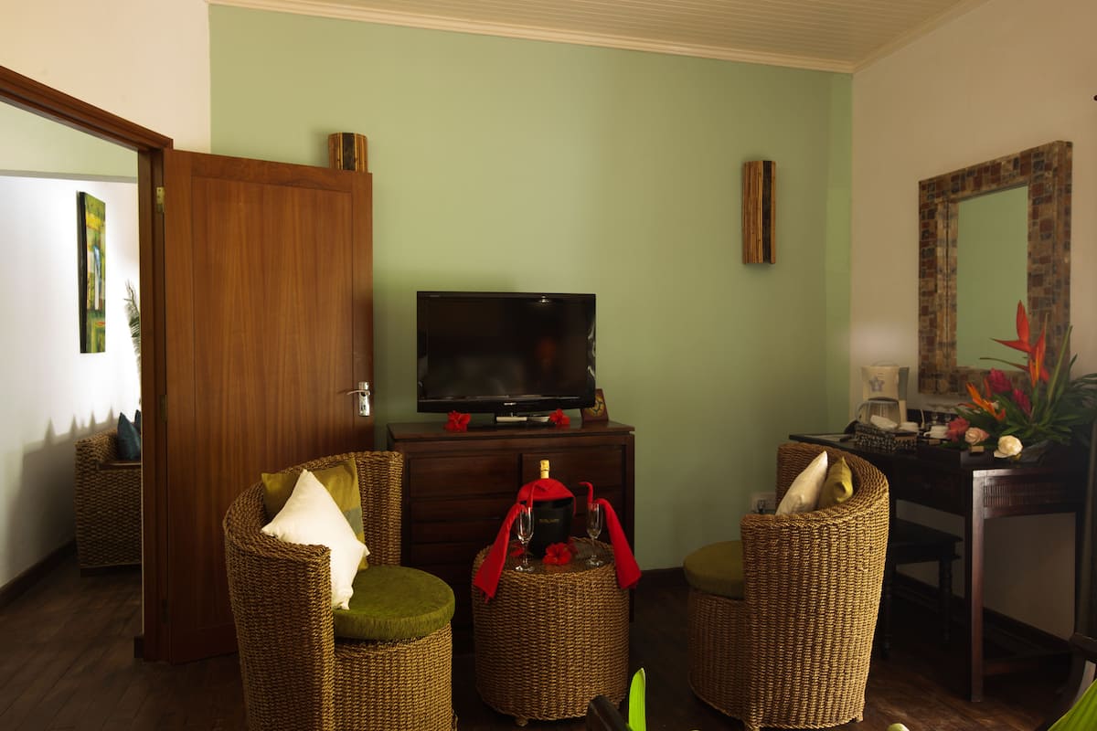 Sala de estar com móveis de vime, televisão e espelho.